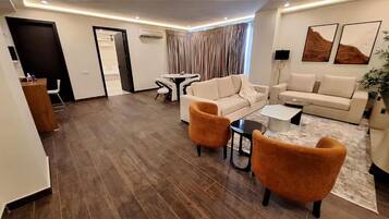 A modern living room with a sofa, two armchairs, a coffee table, and a dining area with a table and chairs.