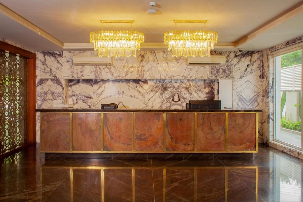 Un área de recepción con pared de mármol, mostrador de recepción y dos candelabros.