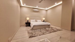 Un dormitorio moderno con cama, mesitas de noche, alfombra e iluminación empotrada en el techo.