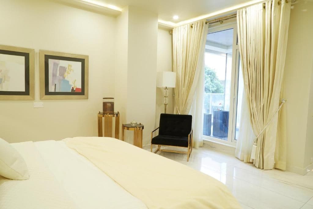 Una habitación de hotel con cama, una silla, una mesita y una ventana con cortinas.