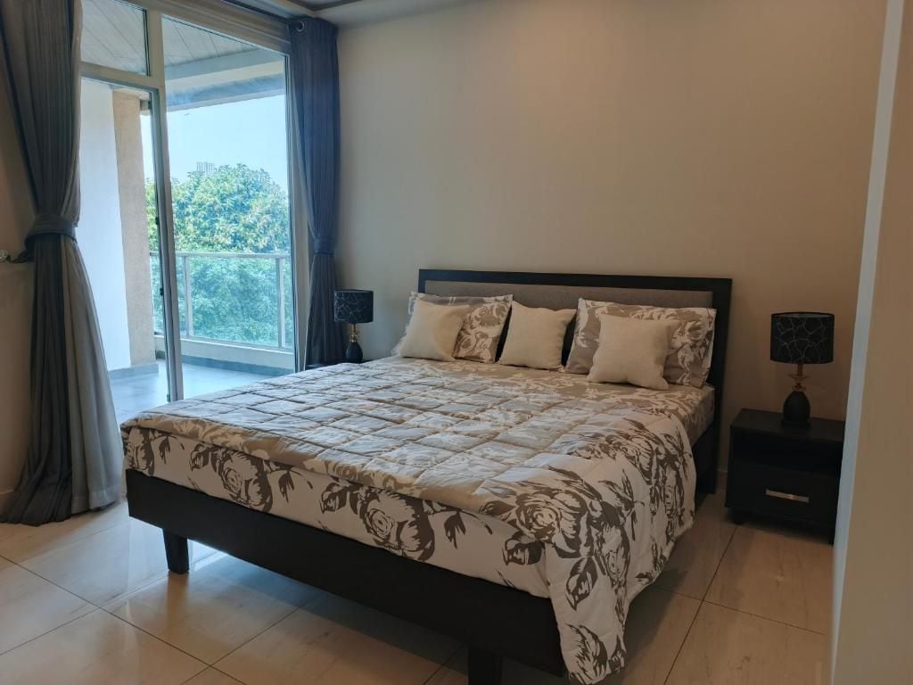 Un dormitorio con cama, cortinas, una mesita de noche y una lámpara.