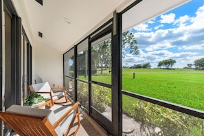 A balcony with a view of a green field and trees. - Fantastic 2-bedroom condo in soothing Palm Beach Gardens (Palm Beach Gardens)