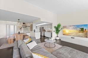 A modern living room with a large sectional sofa, a round coffee table, and a flat-screen TV mounted on the wall. - Fantastic 2-bedroom condo in soothing Palm Beach Gardens (Palm Beach Gardens)