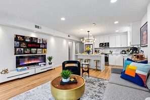 Un salon moderne doté d’un téléviseur à écran plat, d’une cheminée et d’un coin repas avec des tabourets de bar.