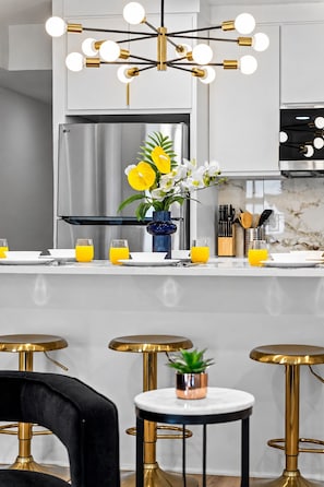 A modern kitchen with a stainless steel refrigerator, a vase with yellow and white flowers, and a bar stool with a copper base. - Chic 1 BR Art Deco-Bishop Arts-Nr Downtown Dallas (Dallas)