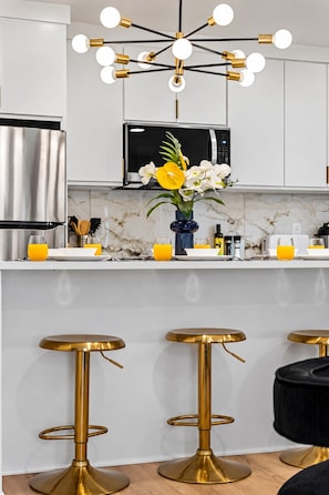 A modern kitchen with a central island, stainless steel appliances, and a decorative light fixture. - Chic 1 BR Art Deco-Bishop Arts-Nr Downtown Dallas (Dallas)
