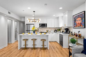 A modern kitchen with white cabinets, a central island with stools, stainless steel appliances, and a pendant light. - Chic 1 BR Art Deco-Bishop Arts-Nr Downtown Dallas (Dallas)