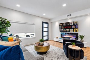 Un salon moderne avec un grand téléviseur à écran plat, une table basse et un canapé.