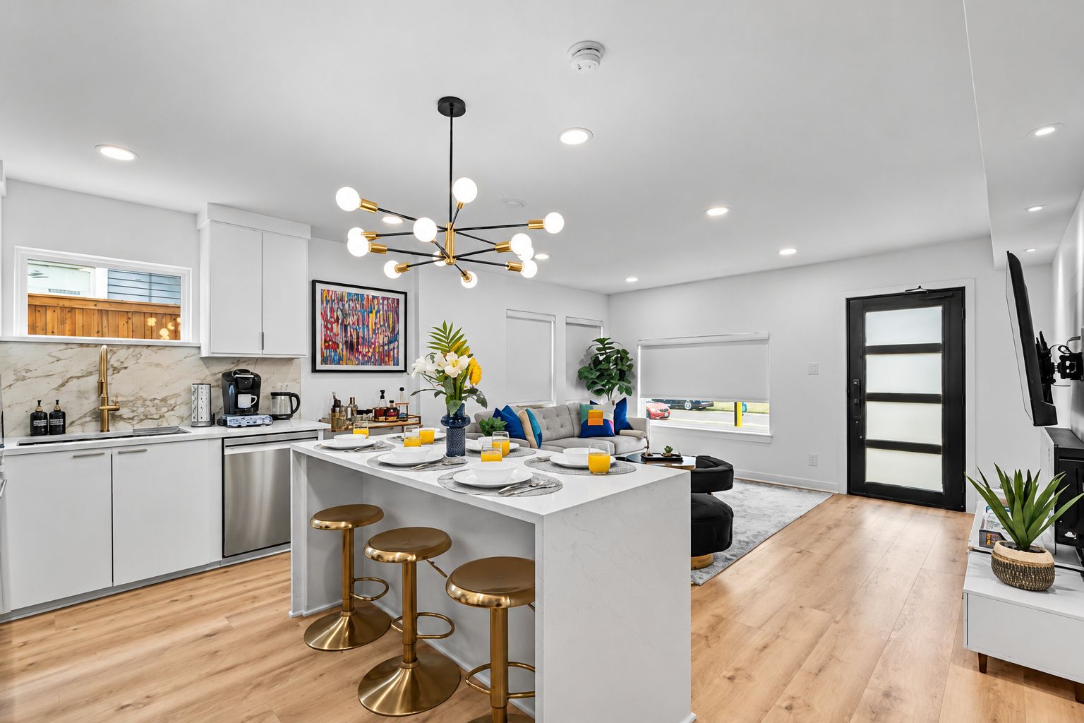 A modern kitchen with a central island, bar stools, a coffee station, and a large window.