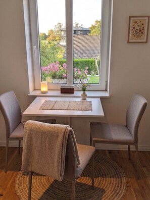A room with a window, a table, two chairs, a lamp, a radio, a vase with flowers, and a rug. - A private apartment, all to yourself. (Møre og Romsdal)