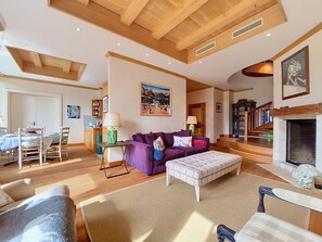 A spacious living room with a high ceiling, wooden beams, a fireplace, and a dining area with a table and chairs. - Le Chamois d'Or A303 by Interhome (Crans-Montana)