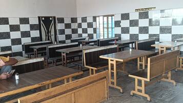 A restaurant with checkered tile walls, wooden tables and benches, and hanging light fixtures.