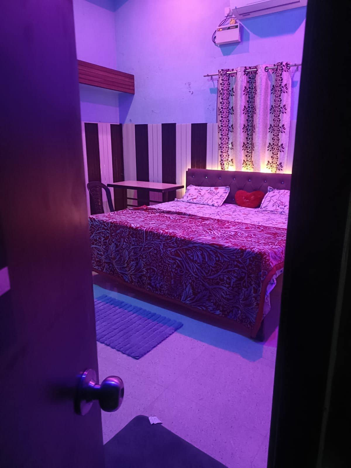 Un dormitorio con una cama, una mesita de noche, una silla y una ventana con cortinas.