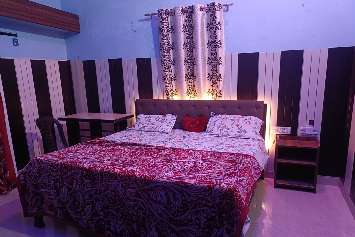 A bedroom with a bed, a bedside table, a chair, and a small table.