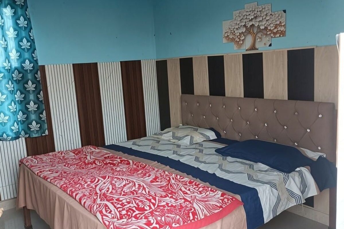 A bedroom with a bed, a wall-mounted tree decoration, and a striped wall panel.