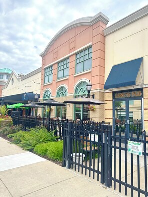 A brick building with a pub sign, outdoor seating, and a black metal fence. - Modern 2 Bedroom Studio Retreat Near Maple-Lawn (Fulton)