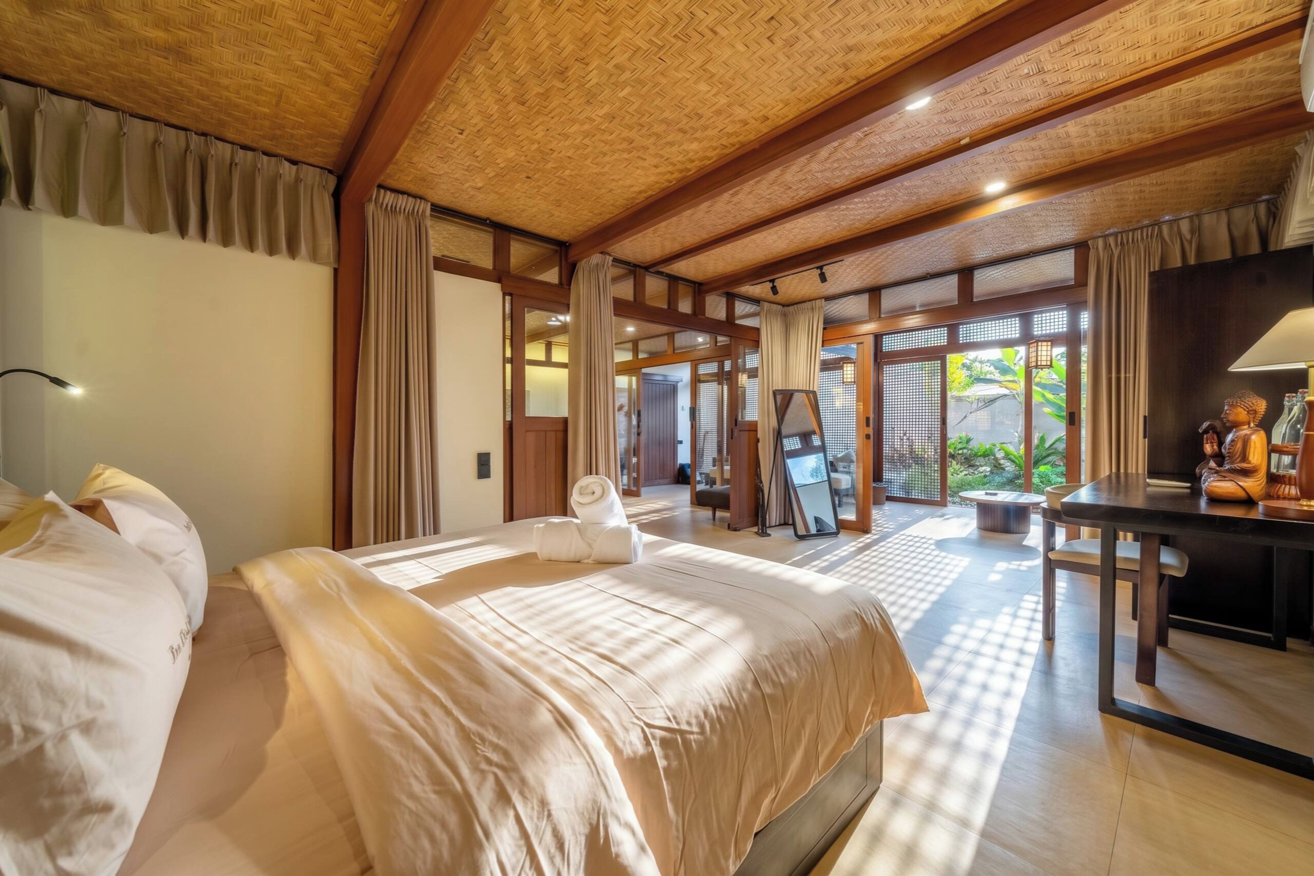 A hotel room with a large bed, a desk, and a view of the garden.