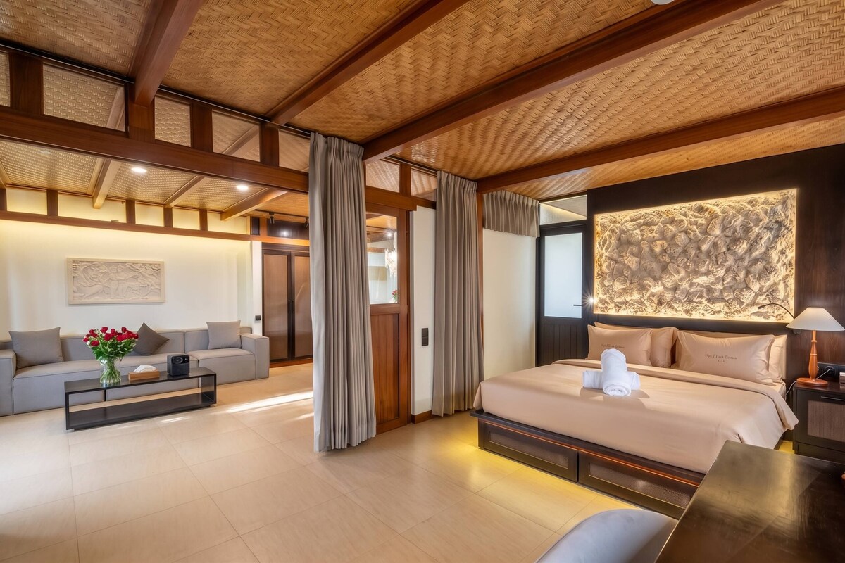 Een moderne hotelkamer met een groot bed, een bank, een bijzettafeltje en een kunstwerk aan de muur.