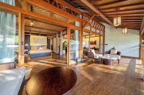 Una habitación amplia con una cama grande, un comedor y vistas al exterior.