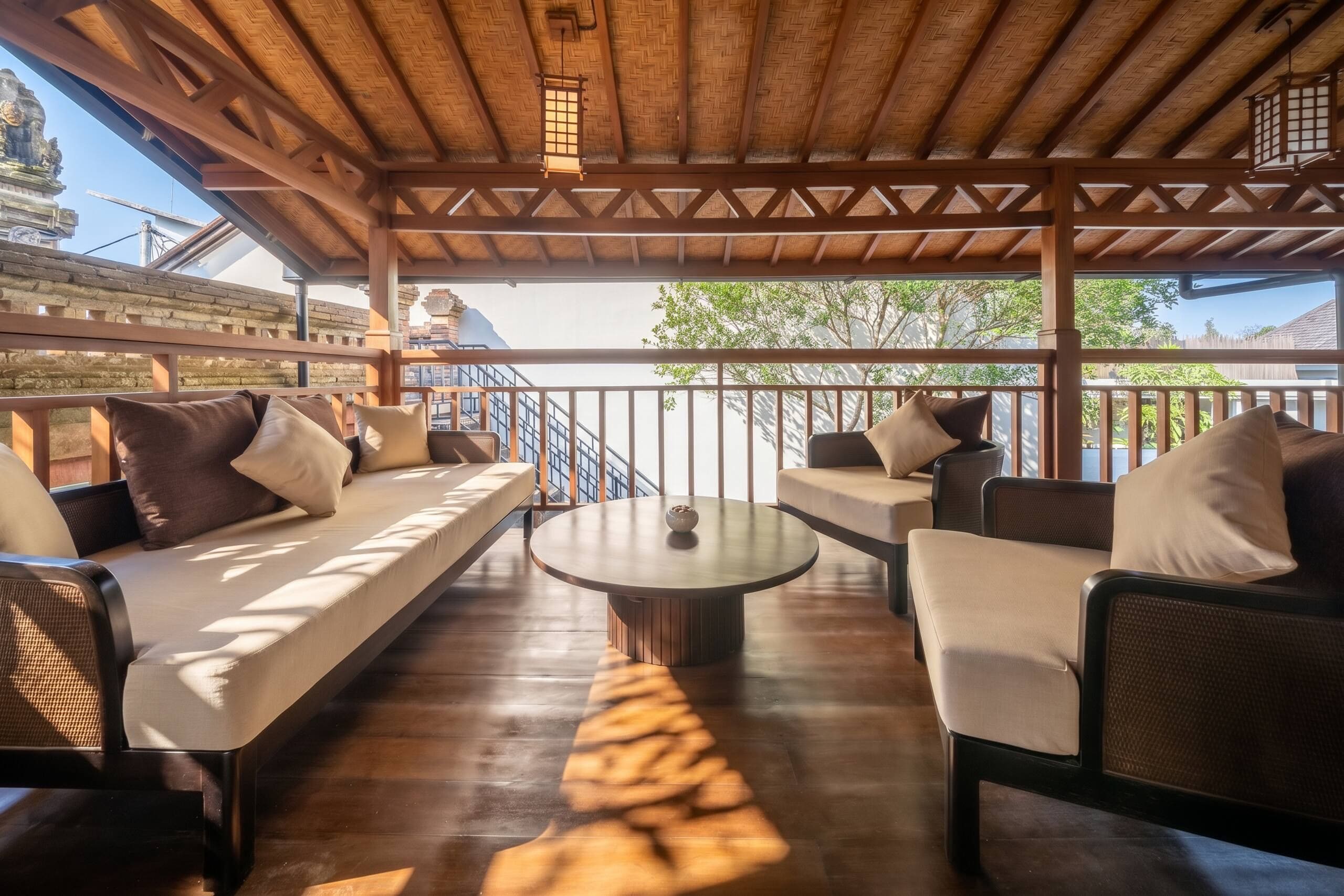 A covered outdoor seating area with cushioned sofas and a central round table.
