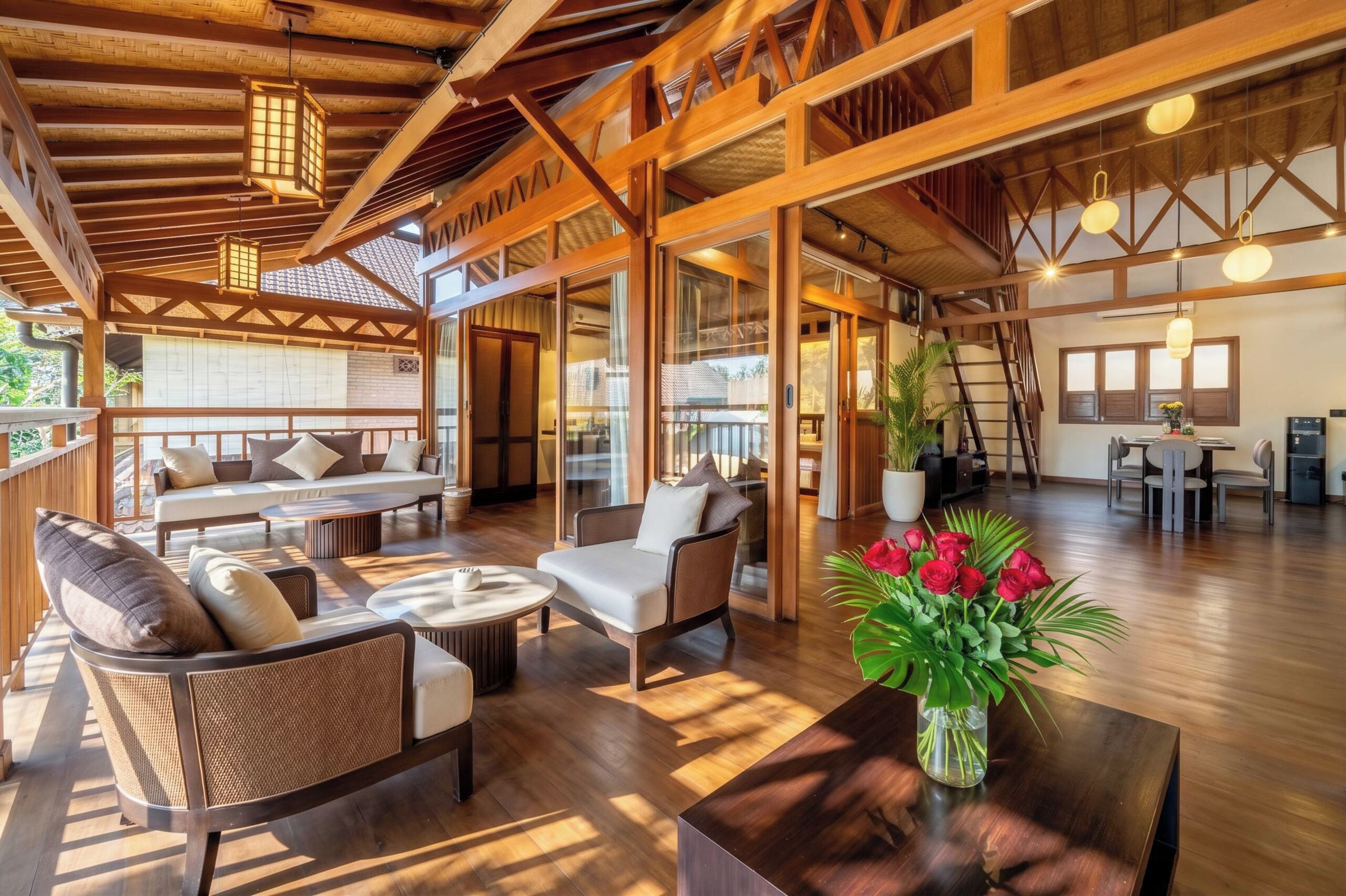 A spacious indoor area with wooden beams, a sofa set, a dining table, and a potted plant.