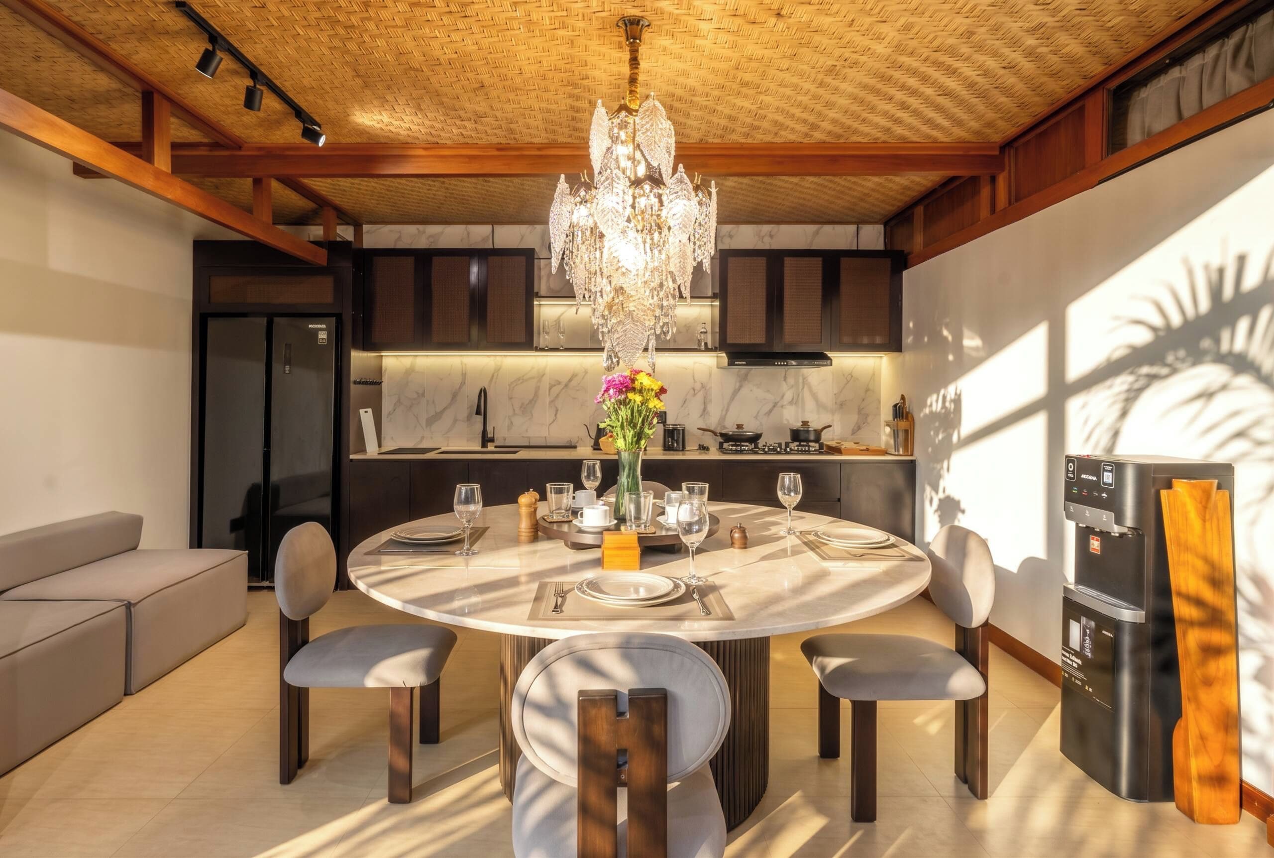 A modern kitchen with a round dining table, chairs, and a chandelier.