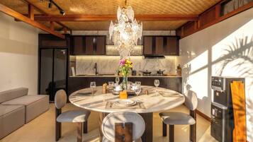 A modern kitchen with a round dining table, chairs, and a chandelier.