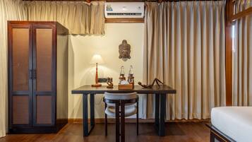 Una habitación con techo de madera, una cama, un escritorio con lámpara, una estatua de Buda y un armario.