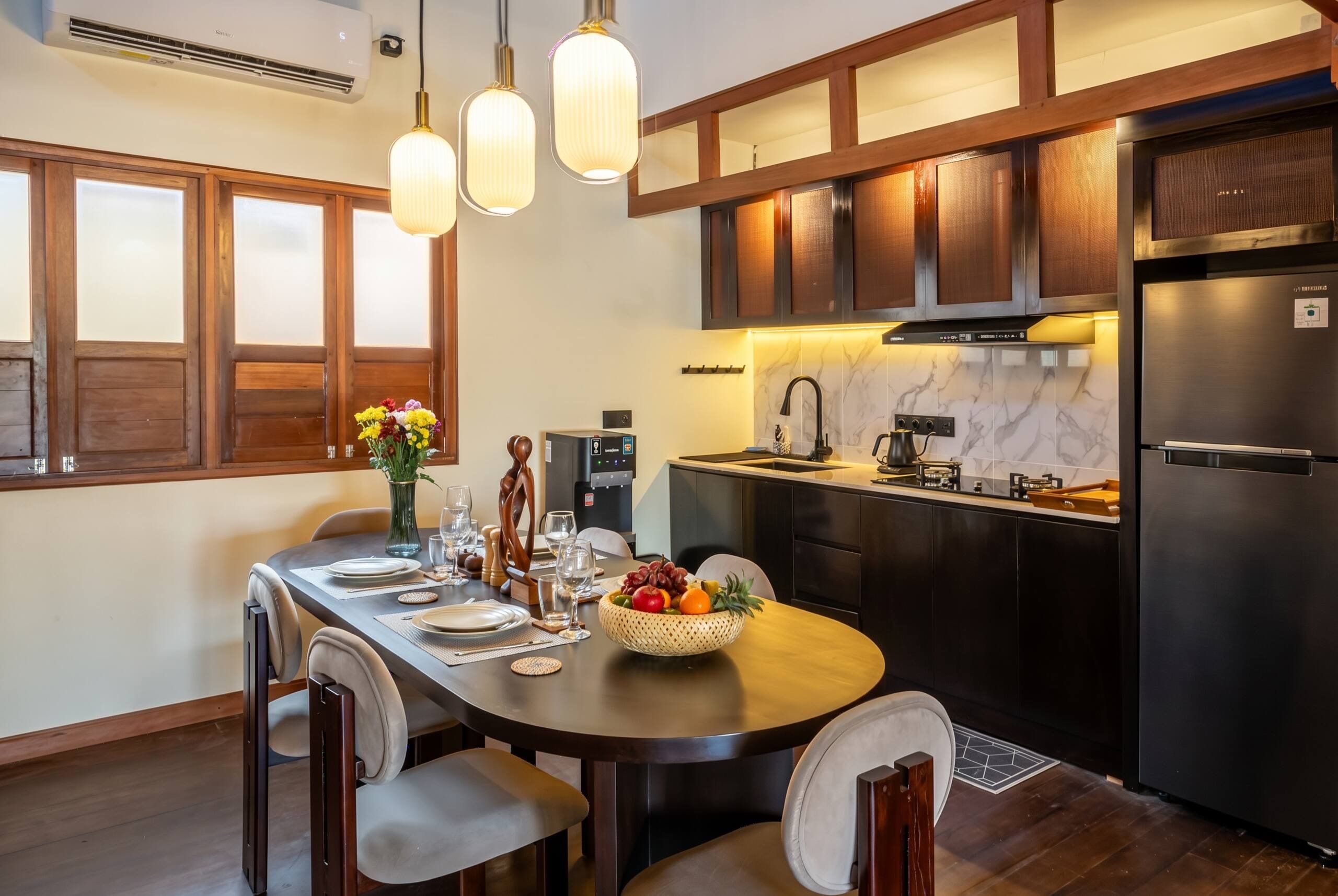 Een moderne keuken met donkerhouten kasten, een roestvrijstalen koelkast, en een eethoek met een houten tafel voor vier personen.