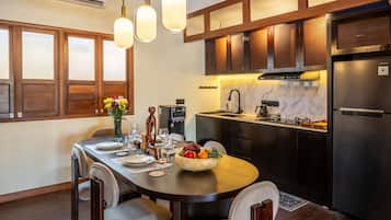 A modern kitchen with dark wood cabinets, a stainless steel refrigerator, and a dining area with a wooden table set for four.