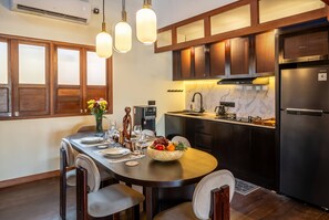 Een moderne keuken met donkerhouten kasten, een roestvrijstalen koelkast, en een eethoek met een houten tafel voor vier personen.