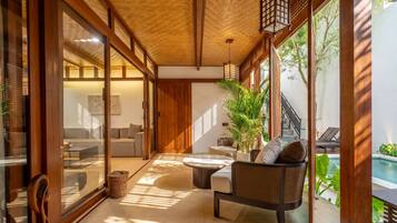 Un interior moderno con techo de madera, puertas de cristal correderas, una zona de estar con mesa redonda y vistas a una piscina.