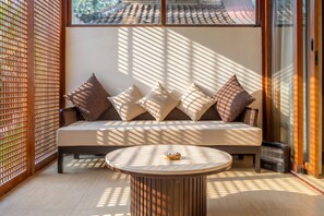 Een moderne woonkamer met een bank, kussens en een ronde salontafel.
