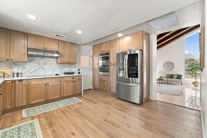 A modern kitchen with wooden cabinets, stainless steel appliances, and a marble countertop. - Welcome to your private retreat situated on over an acre lot with pool/spa (Visalia)