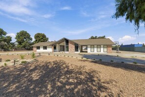 A modern building with a brick facade, large windows, and a sloped roof. - Welcome to your private retreat situated on over an acre lot with pool/spa (Visalia)