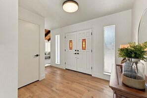 A hallway with wooden flooring, white doors, and a glass enclosure with a plant. - Welcome to your private retreat situated on over an acre lot with pool/spa (Visalia)