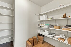 A storage closet with shelves containing folded towels, toiletries, and boxes. - Welcome to your private retreat situated on over an acre lot with pool/spa (Visalia)