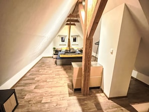 A bedroom with a sloped ceiling, wooden flooring, a bed with pillows, a nightstand, and a window. - Villa Klarka by Interhome (Rokytnice nad Jizerou)