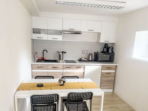 A compact kitchen with white cabinets, a microwave, a coffee maker, and a dining table with two chairs. - Villa Klarka by Interhome (Rokytnice nad Jizerou)