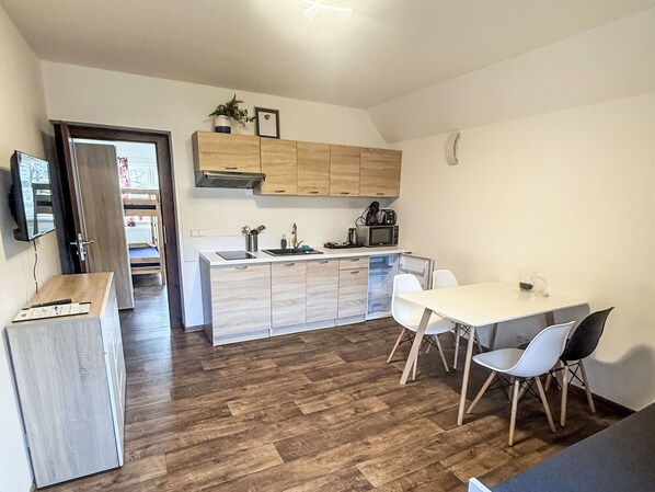 A modern kitchen with wooden cabinets, a central island, and a dining area with chairs. - Villa Klarka by Interhome (Rokytnice nad Jizerou)