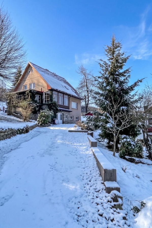 A house with a sloped roof, a stone pathway leading to the entrance, and snow-covered ground. - Klarka 4 by Interhome (Rokytnice nad Jizerou)