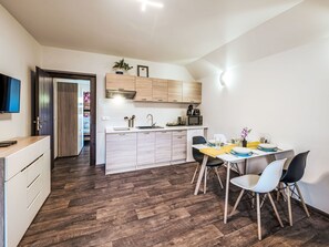 A compact kitchen with modern appliances, a dining area with chairs, and a TV mounted on the wall. - Klarka 3 by Interhome (Rokytnice nad Jizerou)