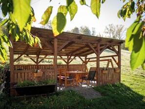 A wooden pergola with a table and chairs, surrounded by a grassy area. - Klarka 3 by Interhome (Rokytnice nad Jizerou)