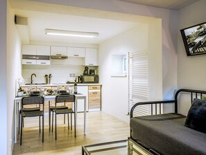 Een functioneel verblijf met kitchenette, eethoek en bed.