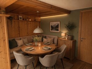 Un coin repas chaleureux avec une table en bois dressée pour quatre personnes, entourée de sièges confortables.