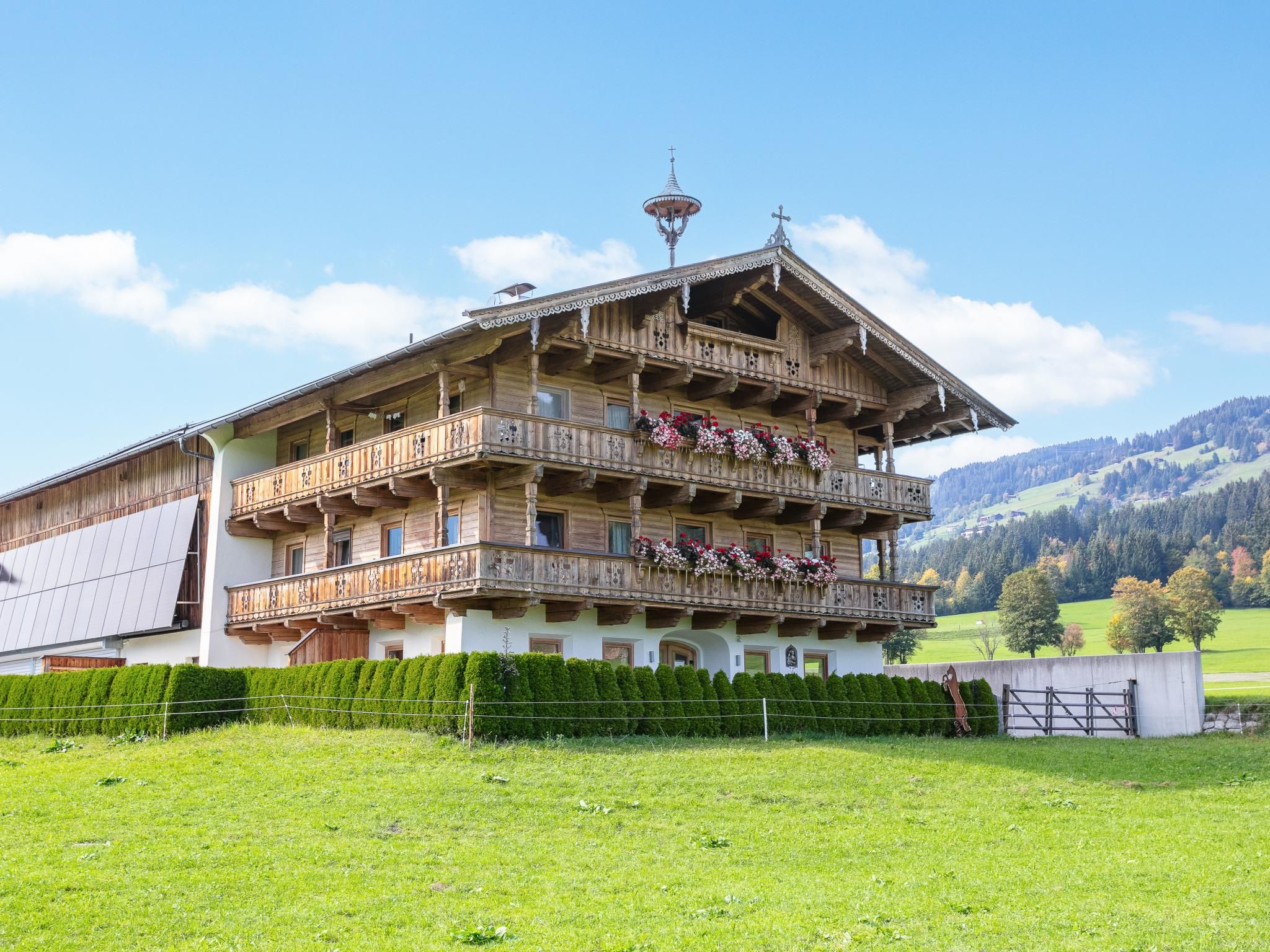 A multi-story wooden building with balconies, surrounded by a well-maintained lawn and a mountainous backdrop.