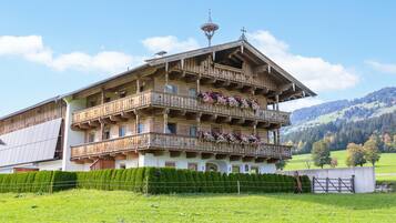 A multi-story wooden building with balconies, surrounded by a well-maintained lawn and a mountainous backdrop.