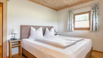 Una camera da letto con un letto, un comodino, una lampada, una finestra con tende e un soffitto in legno.