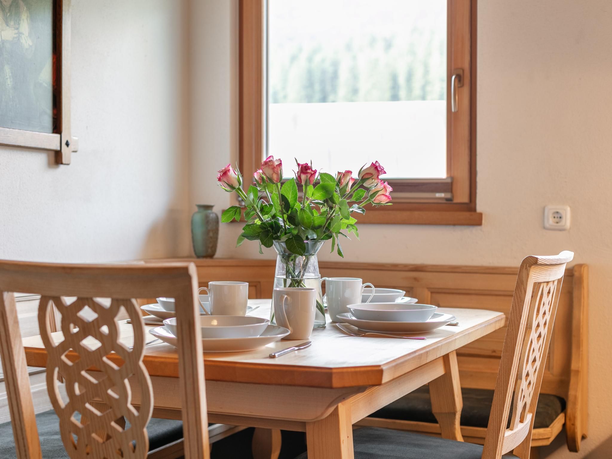 Ett matbord med en vas med blommor, vita tallrikar och koppar.
