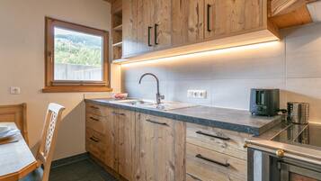 A kitchen with wooden cabinets, a sink, and a window overlooking a landscape.
